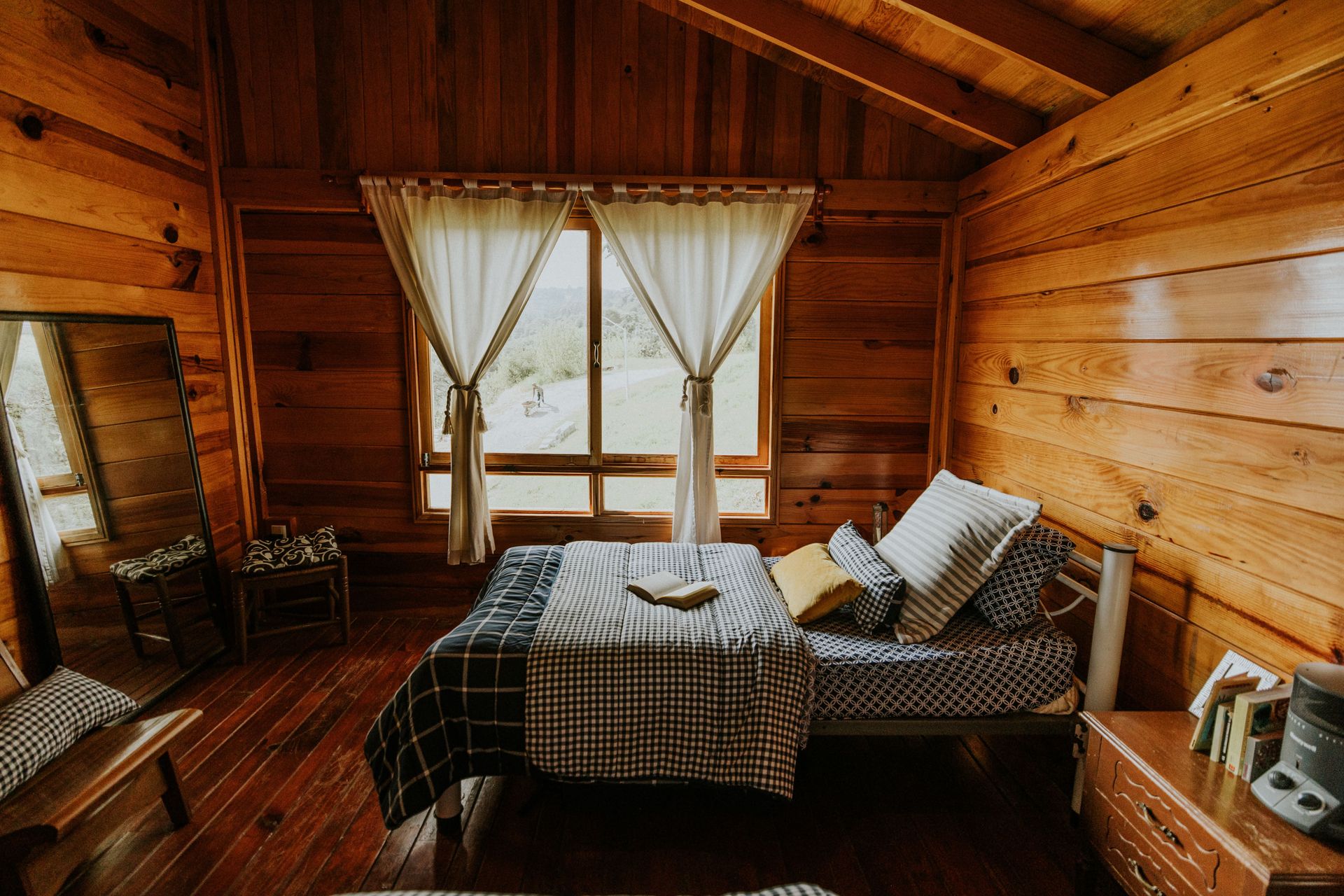 Warm and inviting wooden cabin bedroom featuring a scenic outdoor view with natural light.
